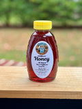 Bottle of Davis & Bates Wildflower Honey on a wooden surface with a blurred natural background